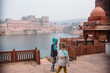 © Amanda Voelker/Stocksy - A little boy and little girl stand in an ancient Indian water temple near a monkey