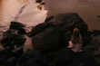 © Amanda Voelker/Stocksy - A young girl on rock in the ocean at sunset