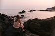 © Amanda Voelker/Stocksy - A young girl on rock in the ocean at sunset