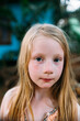 © Amanda Voelker/Stocksy - Portrait of a young girl with freckles in a tropical setting