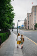 © Amanda Voelker/Stocksy - Two young siblings walks together along a city street in Shanghai