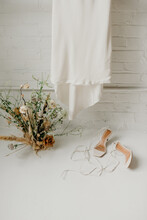 Wedding Dress, Flower Arrangement And High Heel Open Toe Shoes On White Floor