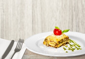 Wall Mural - Tasty hot lasagna dish with tomato sauce and cheese served with tomatoes on a plate