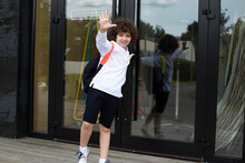 Cute School Boy Is Standing On A Threshold Of A School.