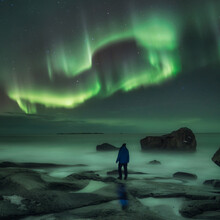 Man Watching Northern Lights At Uttakleiv Beach In Norway