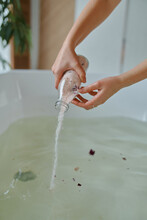 Women's Hands Pour Sea Salt With Flowers In The Bathroom