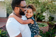 © Erin Brant/Stocksy - Loving dad holding smiling biracial daughter  outdoors