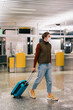 © Alina Hvostikova/Stocksy - Guy with luggage walking in airport terminal