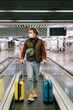 © Alina Hvostikova/Stocksy - Male traveler in mask riding escalator in airport