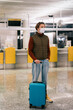 © Alina Hvostikova/Stocksy - Guy with luggage standing in airport terminal