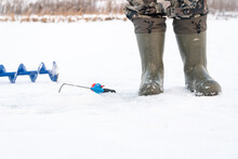 Winter Boots, Fishing Pole And Ice Drill Of A Ice Fisher