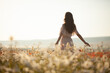 Beautiful girl in summer dress walks in a flower field