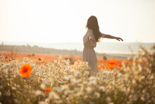 Beautiful Girl In Summer Dress Walks In A Flower Field