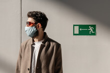 Man In Mask Standing Near Exit Sign