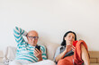 © Studio Firma/Stocksy - A Couple Relaxing in a Bedroom, Using Their Phones