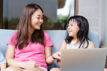 Wall Mural - Happy asian mother and kid girl with laptop computer at home.teacher mother is teach her children during coronavirus covid19 lockdown.Education, Online learning, back to school.School kid.Homeschool.