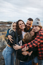 Fun, Cozy Family Group Hug On Rocky Beach At Sunset.