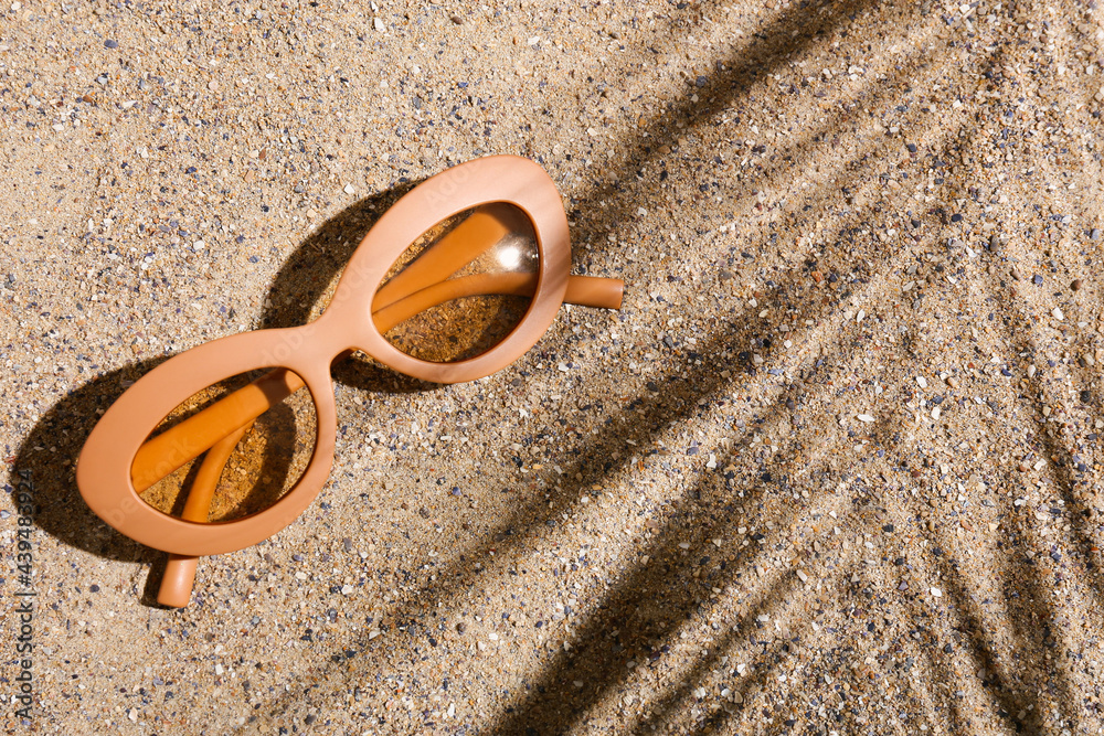 Stylish beach sunglasses on sand