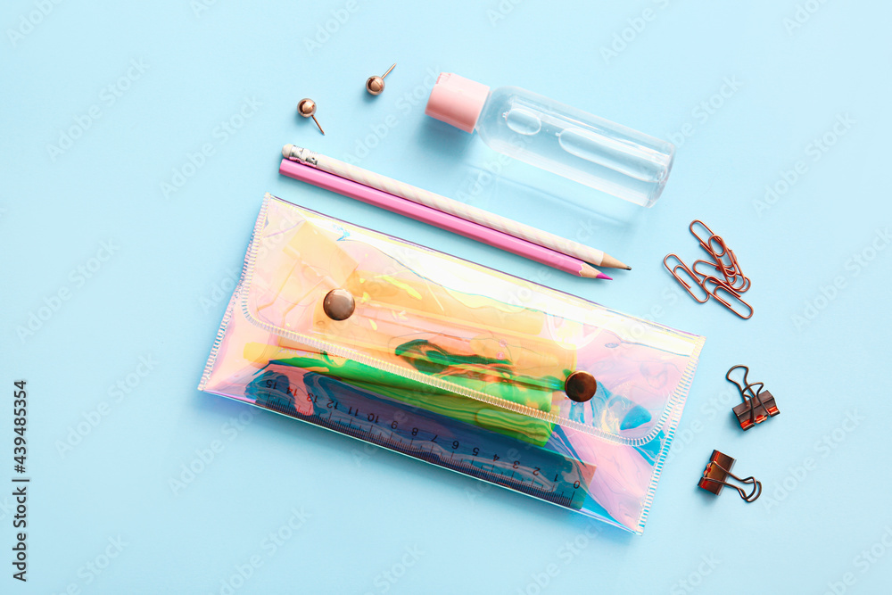 Pencil case with stationery on color background