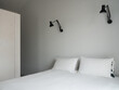 © Laura San Segundo/Stocksy - White bed and black wall lights in a minimalist bedroom