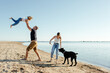 © Sergey Narevskih/Stocksy - Happy young family with dog resting on sandy seashore against cloudless blue sky