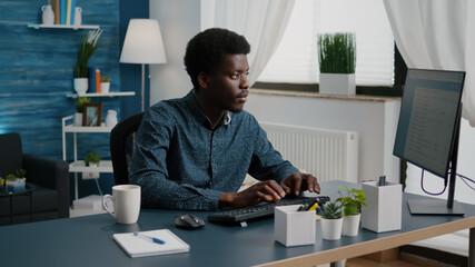 Poster - Authentic black man computer user working from home in cozy flat, remote african american worker typing on computer, freelancer using internet from home office. Online communication, lifestyle and