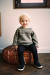 © Melissa Milis Photography/Stocksy - toddler boy sitting on a leather pouf