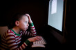 © Jennifer Bogle/Stocksy - Young boy looking frustrated sits at computer