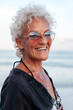 © Viktor Solomin/Stocksy - Smiling elderly woman in sunglasses on beach