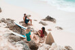 © Alexander Grabchilev/Stocksy - surfers sit on the beach