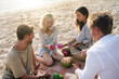 © Alexander Grabchilev/Stocksy - friends having a picnic on the beach