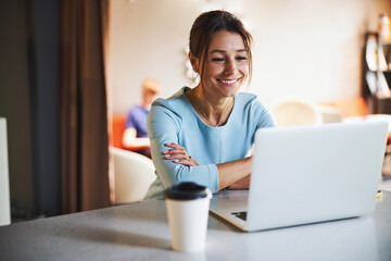happy attractive business lady in blue clothes working on netbook while surfing internet