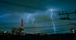 © Tatsuya Kanabe/Stocksy - Electric wires during thunderstorm in city