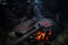 Steak Being Cooked Over An Open Fire In A Shovel