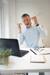 © epiximages - Businessman with blue shirt stands by high table and works with windmill model and is happy