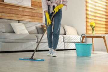 Woman cleaning floor with mop at home, closeup