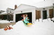 © Maria Manco/Stocksy - kids sledding in front yard