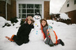 © Maria Manco/Stocksy - kids hug snowman in front yard