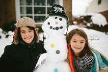 Kids Hug Snowman In Front Yard 