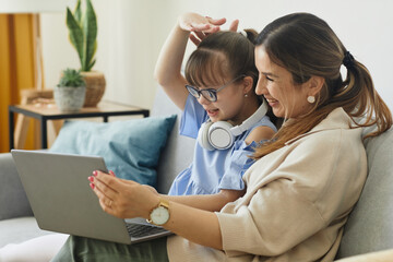 Wall Mural - Portrait of cute girl with disability speaking to camera while using video chat with mom, copy space