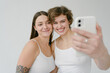 © Roman Shalenkin/Stocksy - Smiling young women taking selfie on smartphone