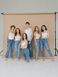 © Roman Shalenkin/Stocksy - Group portrait of diverse people in similar outfits in studio beige background