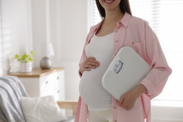 Poster - Young pregnant woman with scales at home, closeup