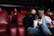 Movies: Masked Friends Look At Phone During Movie