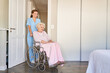 Altenpflegerin oder Pflegehilfe schiebt Seniorin im Rollstuhl