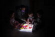 © Javier Pardina/Stocksy - Children playing with a light board in the dark