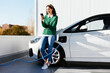 © BONNINSTUDIO/Stocksy - Woman using smartphone near electric car on charging station