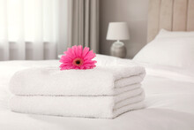 Stack Of Fresh Towels With Flower On Bed Indoors