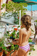 © ADDICTIVE STOCK - crop girl in swimwear watering plants with hosepipe