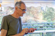© Anna Berkut/Stocksy - banking online, senior elderly man using smartphone at home, mobile internet on the phone